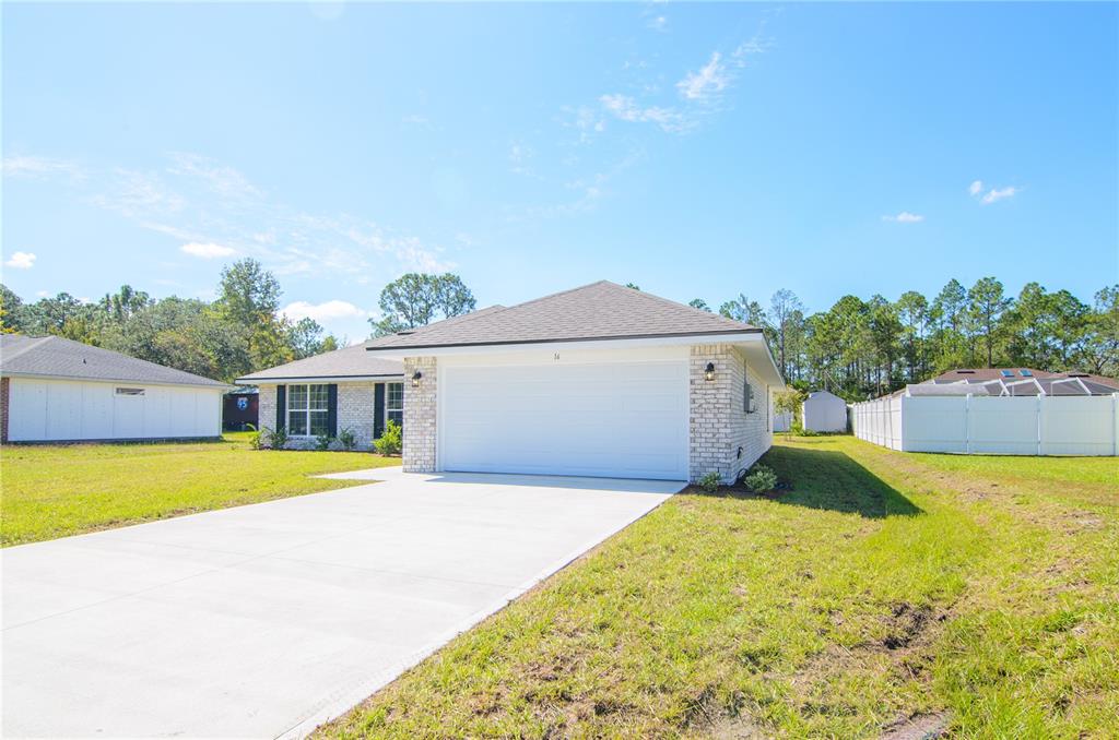 A single-story house with a white brick facade, a two-car garage, and a concrete driveway — 57 RADCLIFFE DRIVE, PALM COAST, FL