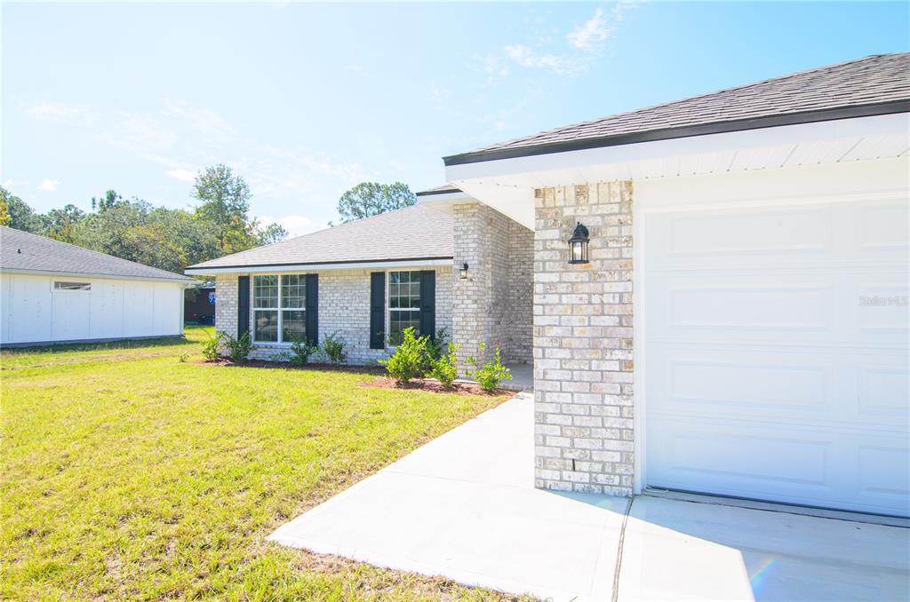 A single-story house with a brick facade, white garage door, and black window shutters — 57 RADCLIFFE DRIVE, PALM COAST, FL