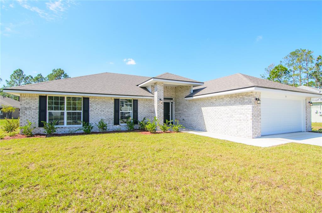 A single-story house with a white brick exterior, a two-car garage, and black shutters — 57 RADCLIFFE DRIVE, PALM COAST, FL