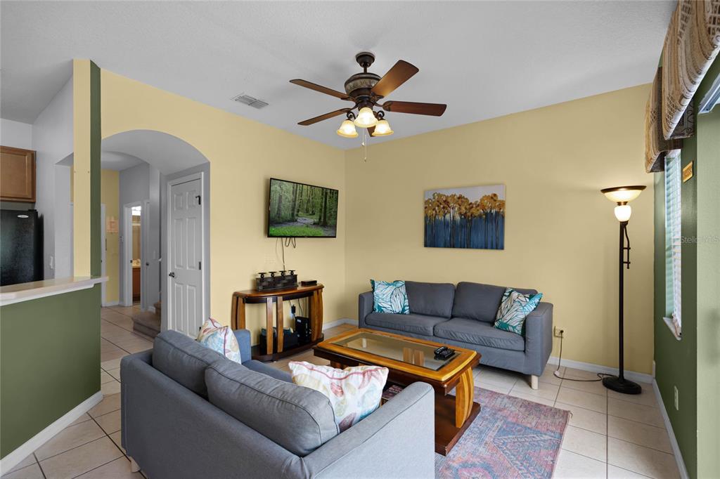 A living room features two gray sofas, a coffee table, a television, and tile flooring — 3083 YELLOW LANTANA LANE, KISSIMMEE, FL
