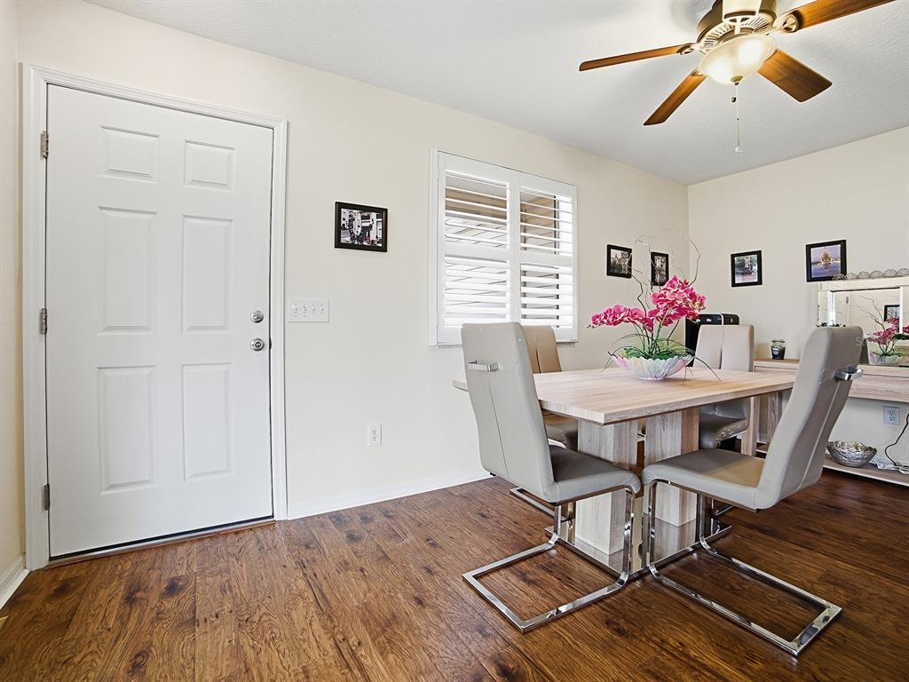 A dining room features wood-look flooring, a light wood table, and modern chairs — 258 ARBELLA LOOP, THE VILLAGES, FL