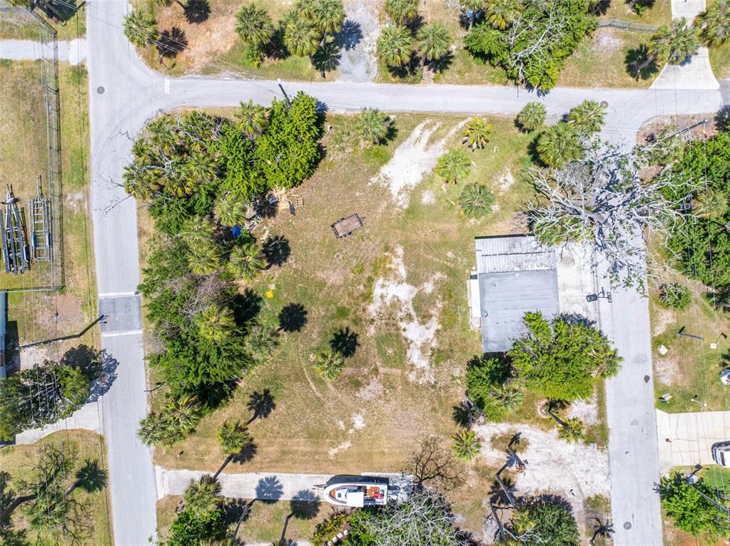 An aerial view shows a vacant lot with a small building, trees, and parked vehicles — 4824 DOWELL DRIVE, PORT RICHEY, FL