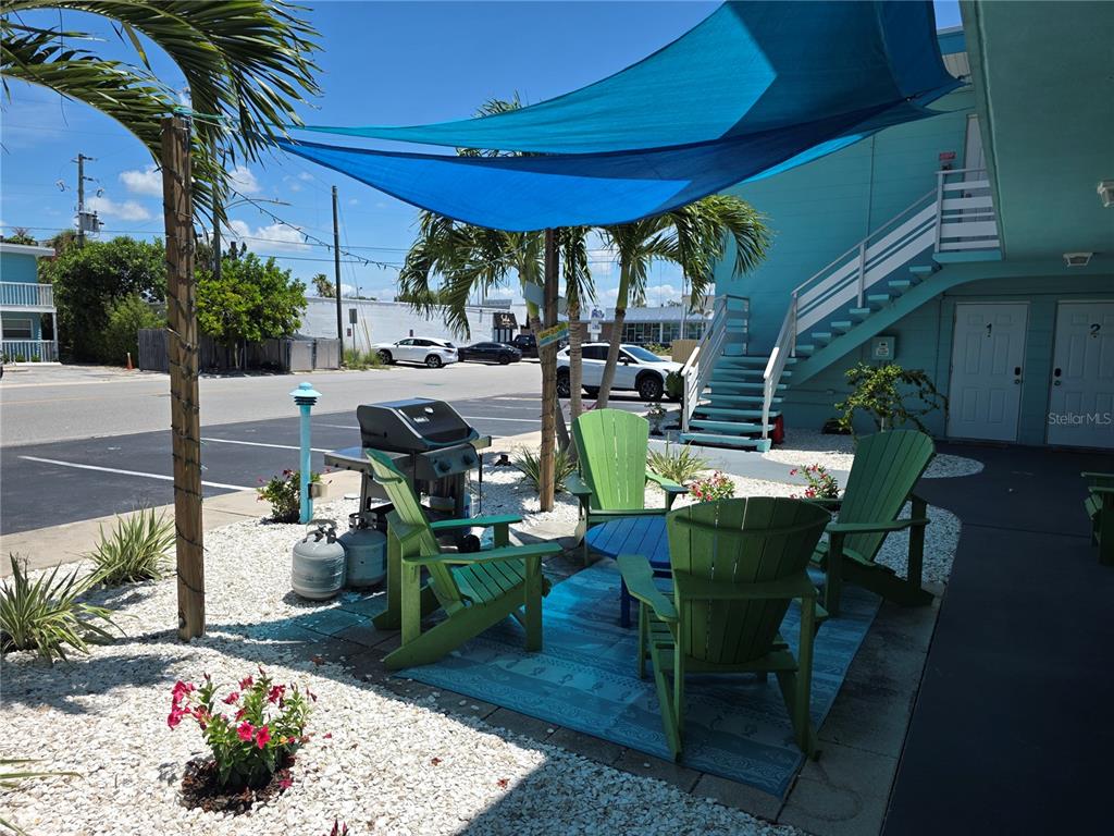 A patio area features green Adirondack chairs, a grill, and a blue shade sail — 504 67TH AVENUE UNIT 12, ST PETE BEACH, FL