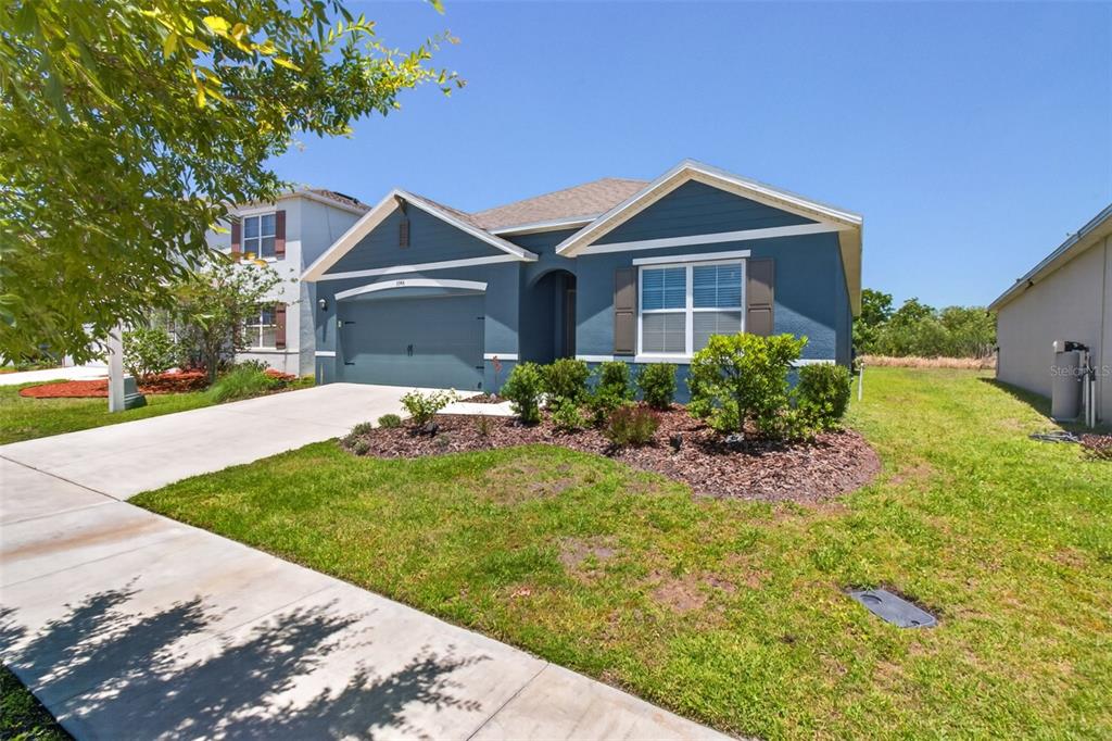 A blue single-story house with a two-car garage and a landscaped front yard — 5946 SHINGLE CREEK ROAD, LAKELAND, FL