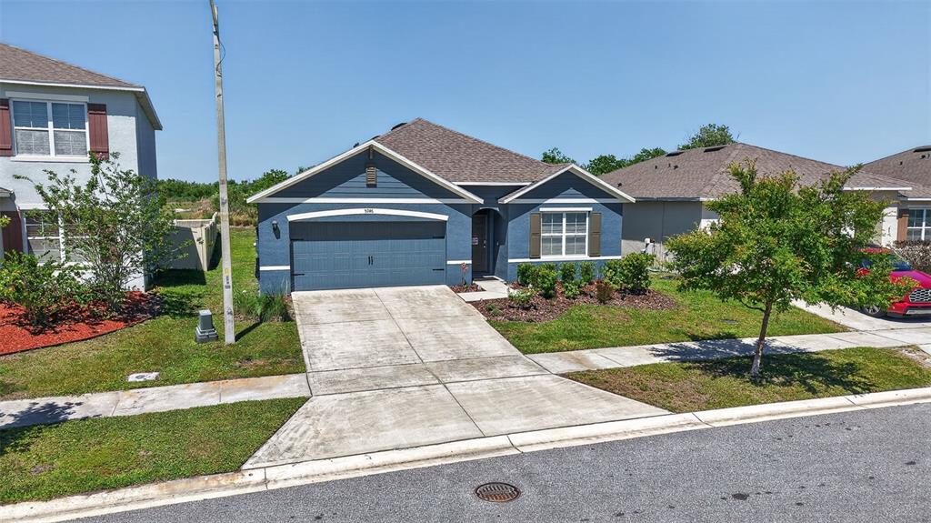 A kitchen features gray cabinets, granite countertops, a central island with stools, and tile flooring — 5946 SHINGLE CREEK ROAD, LAKELAND, FL