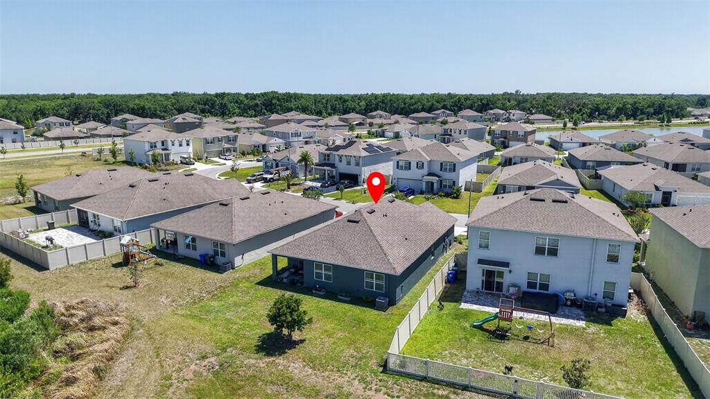 A kitchen features a granite-topped island with three stools, gray cabinets, and stainless steel appliances — 5946 SHINGLE CREEK ROAD, LAKELAND, FL