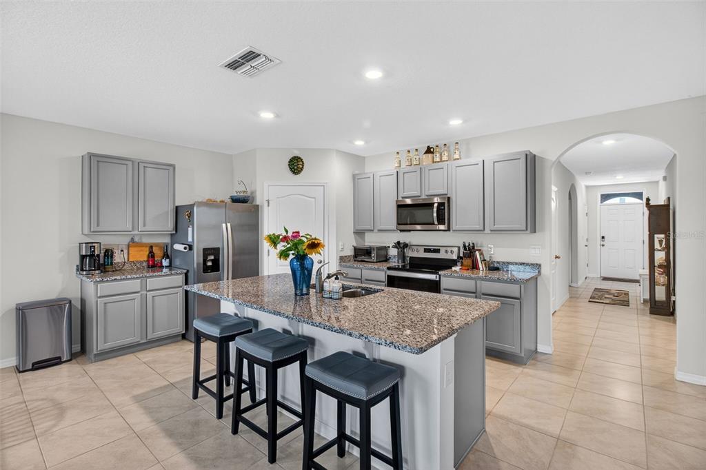 A kitchen with a granite island and stainless steel appliances opens to a living area — 5946 SHINGLE CREEK ROAD, LAKELAND, FL