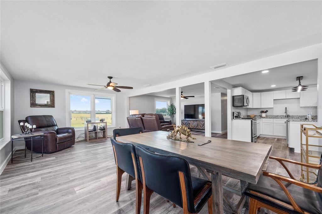 An open-concept living and dining area features wood-look flooring, white cabinetry, and a large window — 1231 NW 102ND BOULEVARD, WILDWOOD, FL