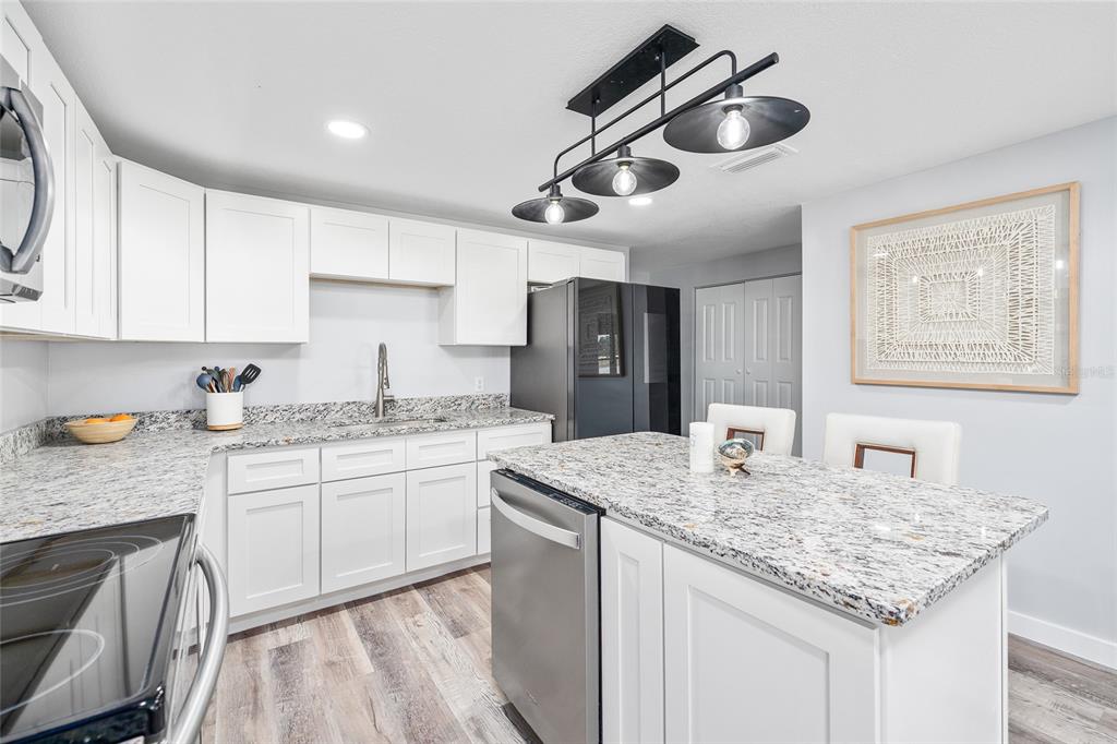 A kitchen features white cabinets, granite countertops, stainless steel appliances, and a central island — 1231 NW 102ND BOULEVARD, WILDWOOD, FL