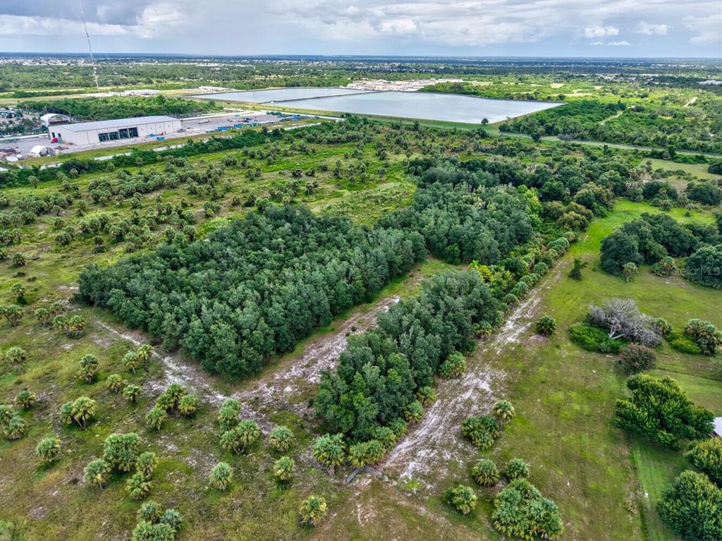 An aerial view shows a large, undeveloped plot of land with patches of dense trees — 3321 ROWLAND DRIVE UNIT Tract E, PUNTA GORDA, FL