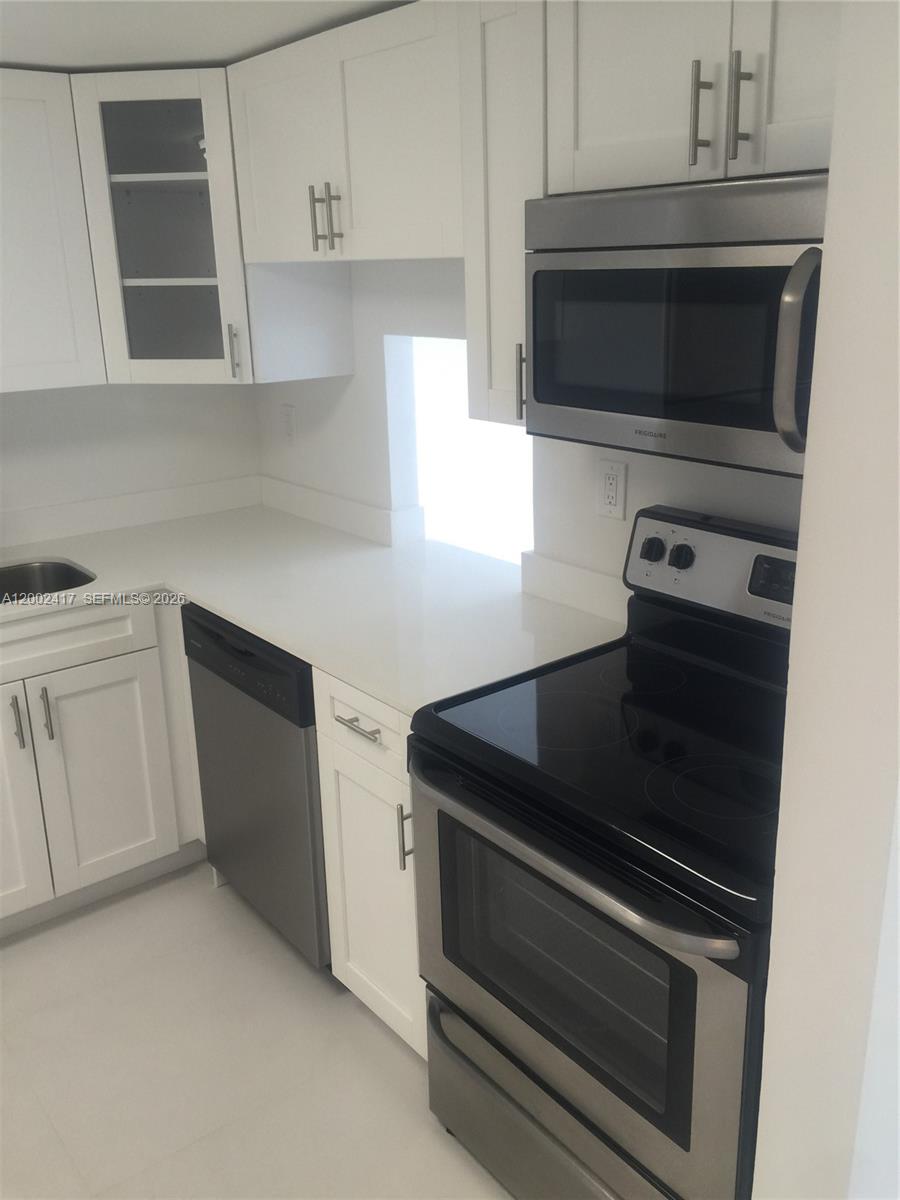 A kitchen features white cabinets, stainless steel appliances, and light-colored countertops — 6900 Bay Dr # 5A, Miami Beach FL 33141, MIAMI BEACH, FL
