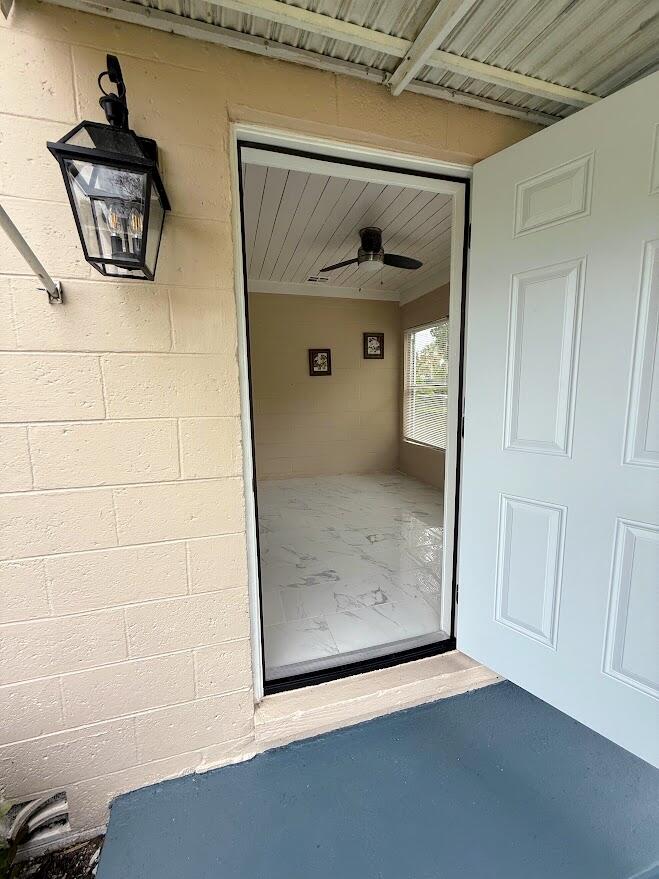 A view through an open white door into a sunroom with marble-look tile flooring — 1010 Mayflower Road, Fort Pierce FL 34950, FORT PIERCE, FL