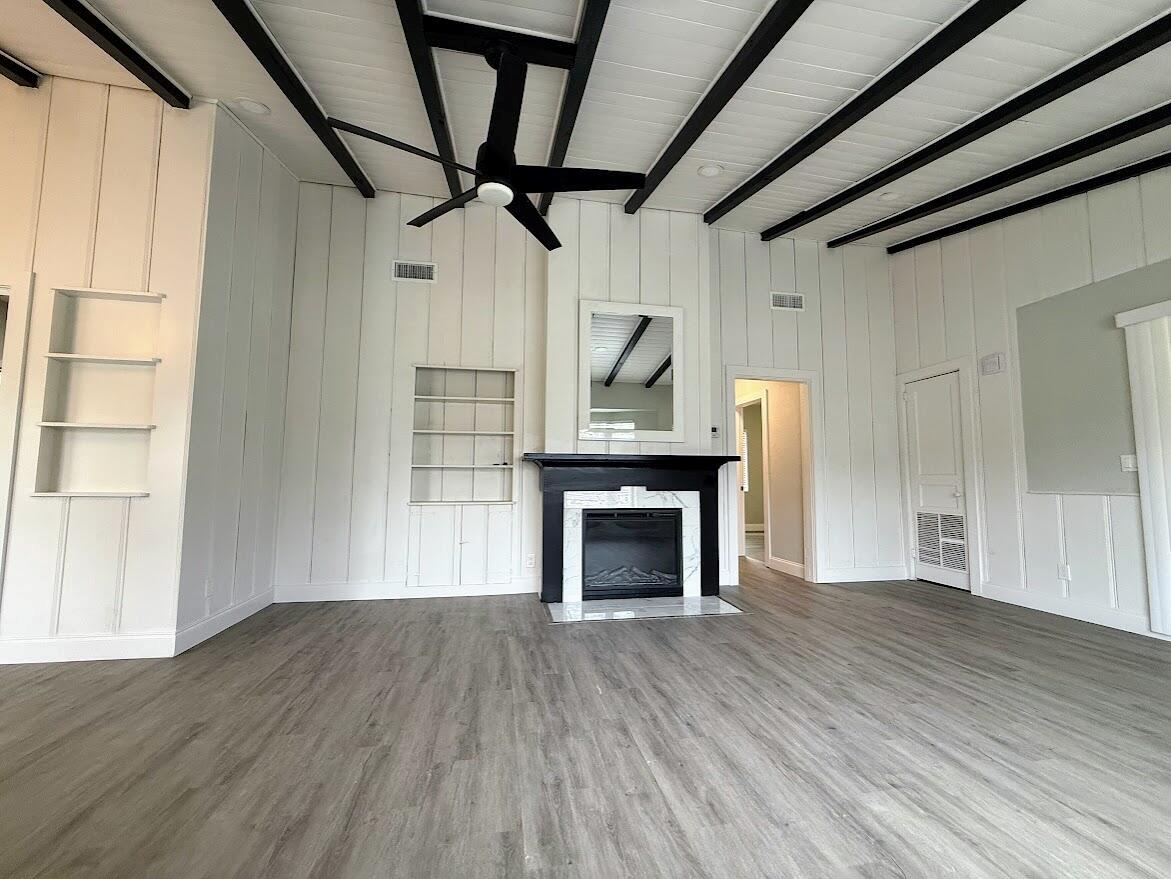 A living room with white vertical paneling, black ceiling beams, and a black fireplace — 1010 Mayflower Road, Fort Pierce FL 34950, FORT PIERCE, FL