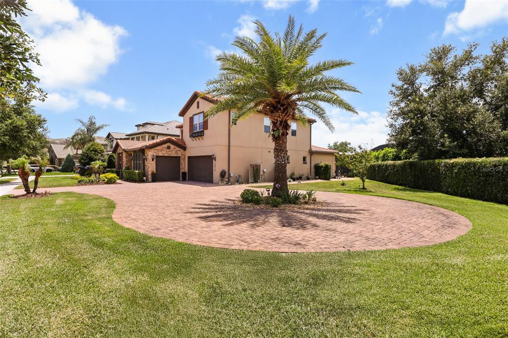 A two-story house with a brick paver driveway and a large palm tree in front — 16614 HARBOR SAIL WAY, WINTER GARDEN, FL