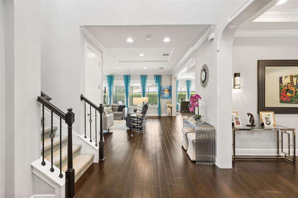 A view from a foyer looking into a living room with dark hardwood floors and stairs — 16614 HARBOR SAIL WAY, WINTER GARDEN, FL