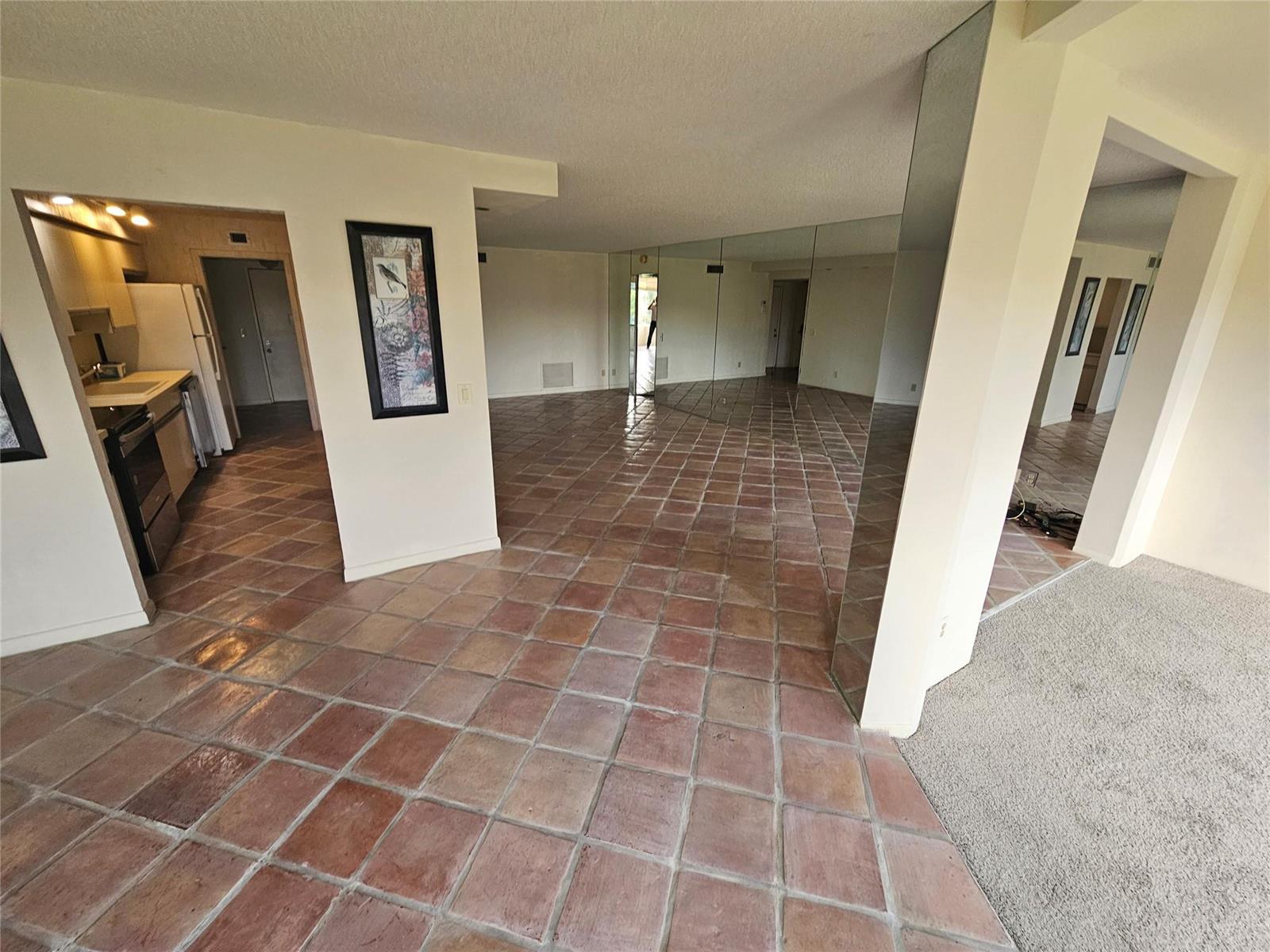 An open-concept living area features terracotta tile flooring, mirrored walls, and an adjacent kitchen — 4770 Fountains Drive S # 303, FL 33467, FL