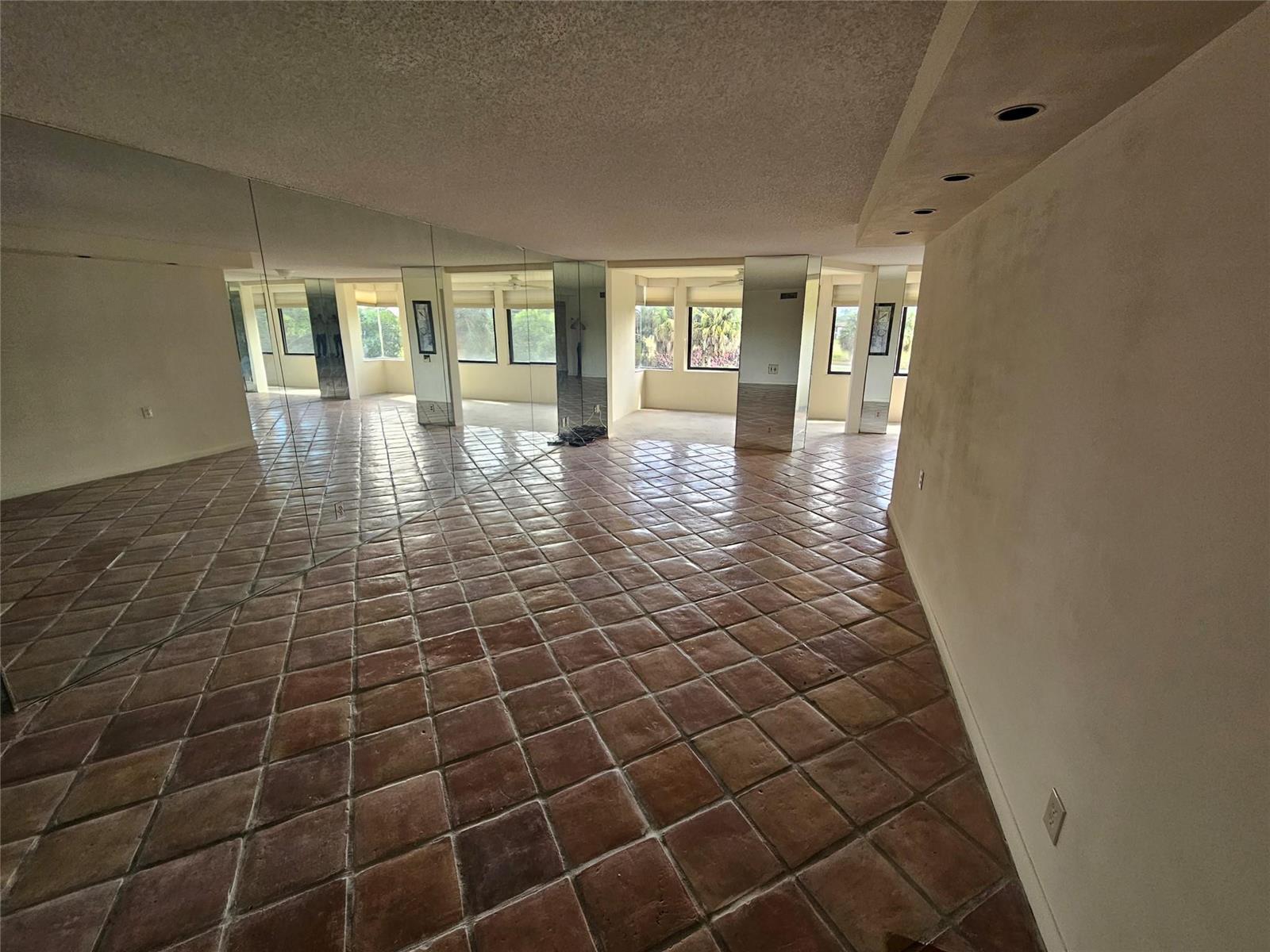 An empty room features terracotta tile flooring, mirrored walls, and recessed ceiling lighting — 4770 Fountains Drive S # 303, FL 33467, FL