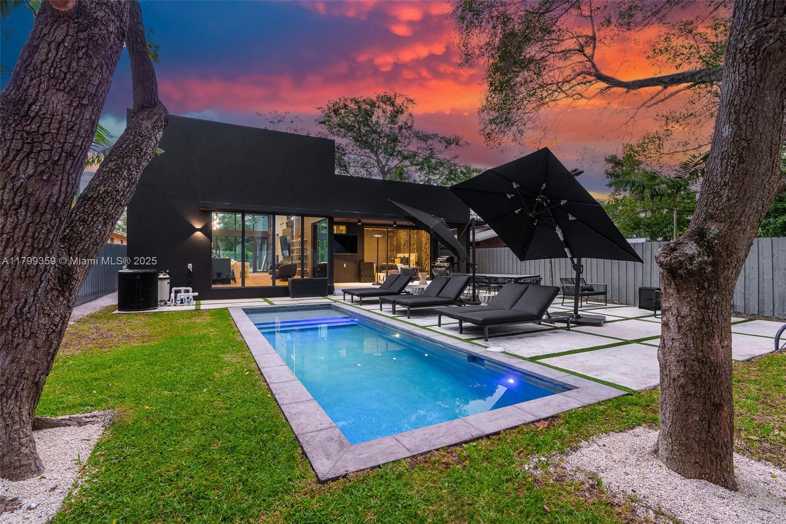 A modern black house features a rectangular swimming pool, patio furniture, and large trees outdoors — 400 NW 49th St # 0, Miami FL 33127, MIAMI, FL