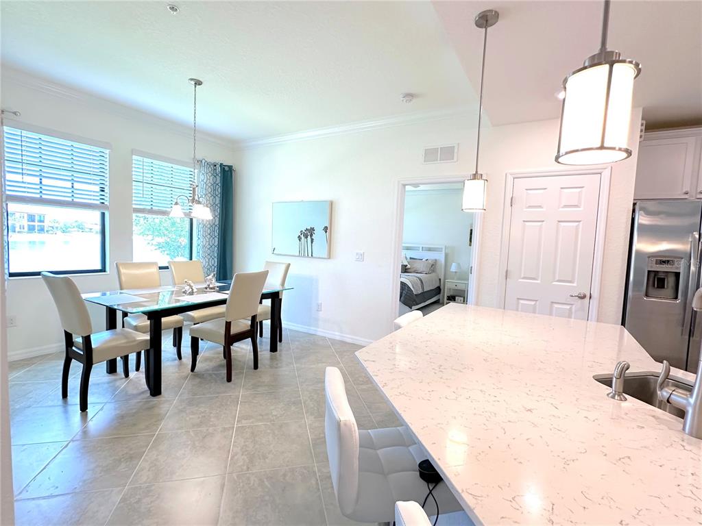 A kitchen with a quartz island and dining area featuring a glass table and chairs — 10054 CROOKED CREEK DRIVE UNIT 102, VENICE, FL