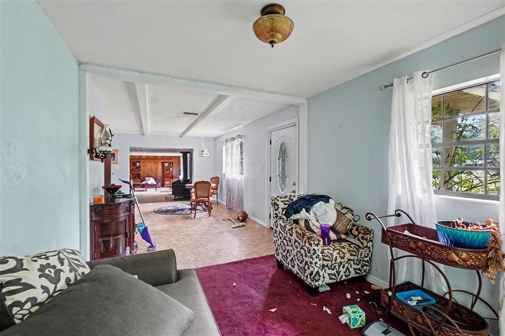 A living room with light blue walls, a patterned armchair, and an open dining area — 3220 GARDNER ROAD, LAKELAND, FL