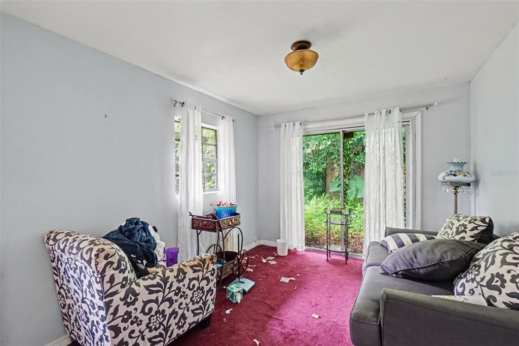 A living room with red carpet, a patterned armchair, a gray sofa, and sliding glass doors — 3220 GARDNER ROAD, LAKELAND, FL