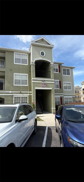 A three-story apartment building exterior features light green siding and a central covered stairwell entrance — 8103 LILLIES WAY UNIT 108, ORLANDO, FL