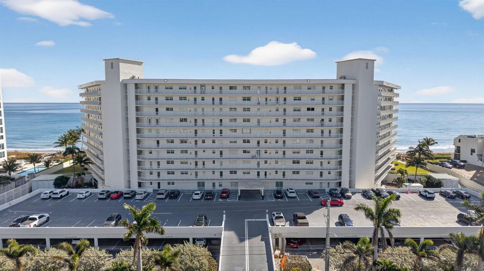 An aerial view shows a multi-story beachfront apartment building with an adjacent parking lot — 3101 S Ocean Boulevard # 302, Highland Beach FL 33487, HIGHLAND BEACH, FL