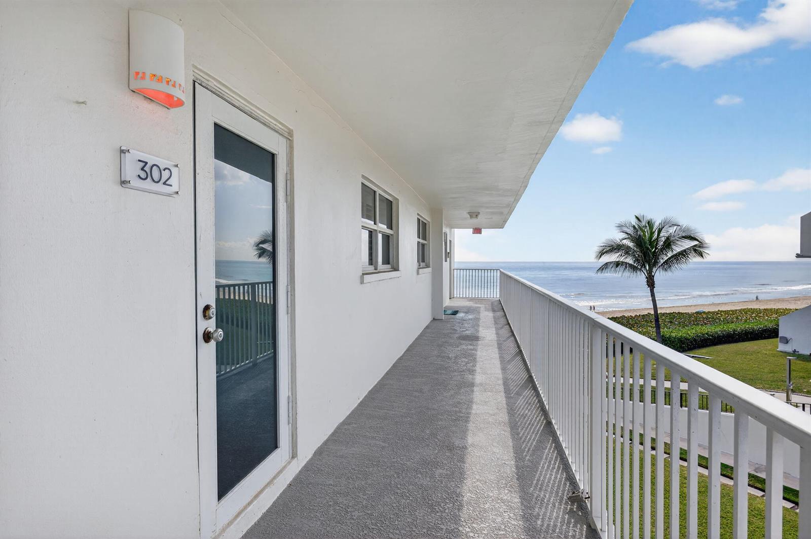 An exterior balcony with a white railing overlooks the ocean and a palm tree — 3101 S Ocean Boulevard # 302, Highland Beach FL 33487, HIGHLAND BEACH, FL