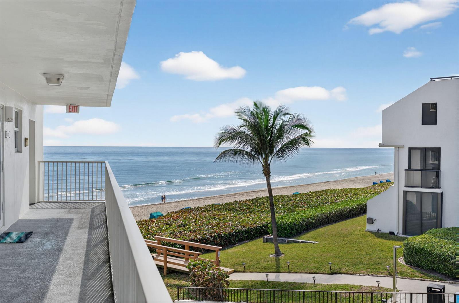 An elevated balcony overlooks a beach, a palm tree, and a neighboring building — 3101 S Ocean Boulevard # 302, Highland Beach FL 33487, HIGHLAND BEACH, FL