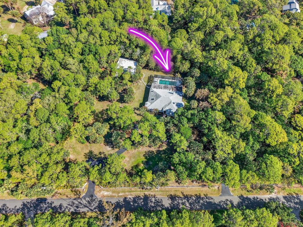 An aerial view shows a house with a pool surrounded by dense forest and trees — 9417 Whippoorwill Trail, FL 33478, FL