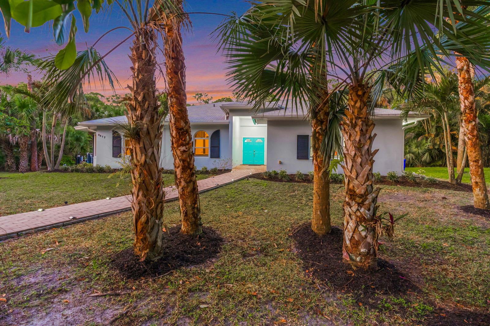 A single-story house with a turquoise front door and a brick walkway surrounded by palm trees — 9417 Whippoorwill Trail, FL 33478, FL