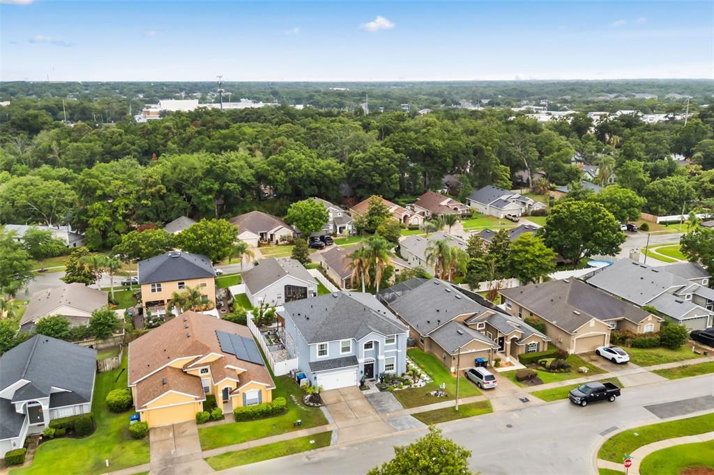 An aerial view shows a suburban neighborhood with single-family homes, green lawns, and dense trees — 2408 CIMMARON ASH WAY, APOPKA, FL