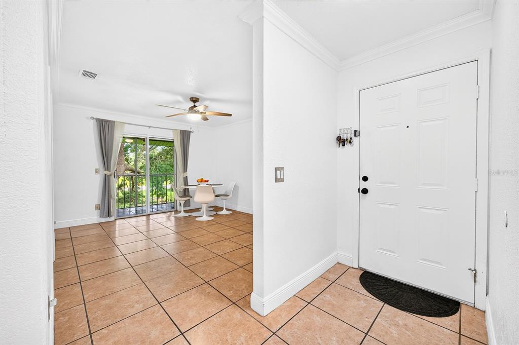 An entryway with tile flooring leads into a dining area featuring a sliding glass door — 4336 HECTOR COURT UNIT 7, ORLANDO, FL