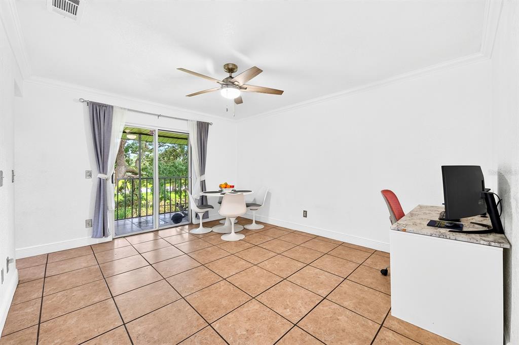 A room with tile flooring, a dining set, a desk, and sliding doors to a balcony — 4336 HECTOR COURT UNIT 7, ORLANDO, FL