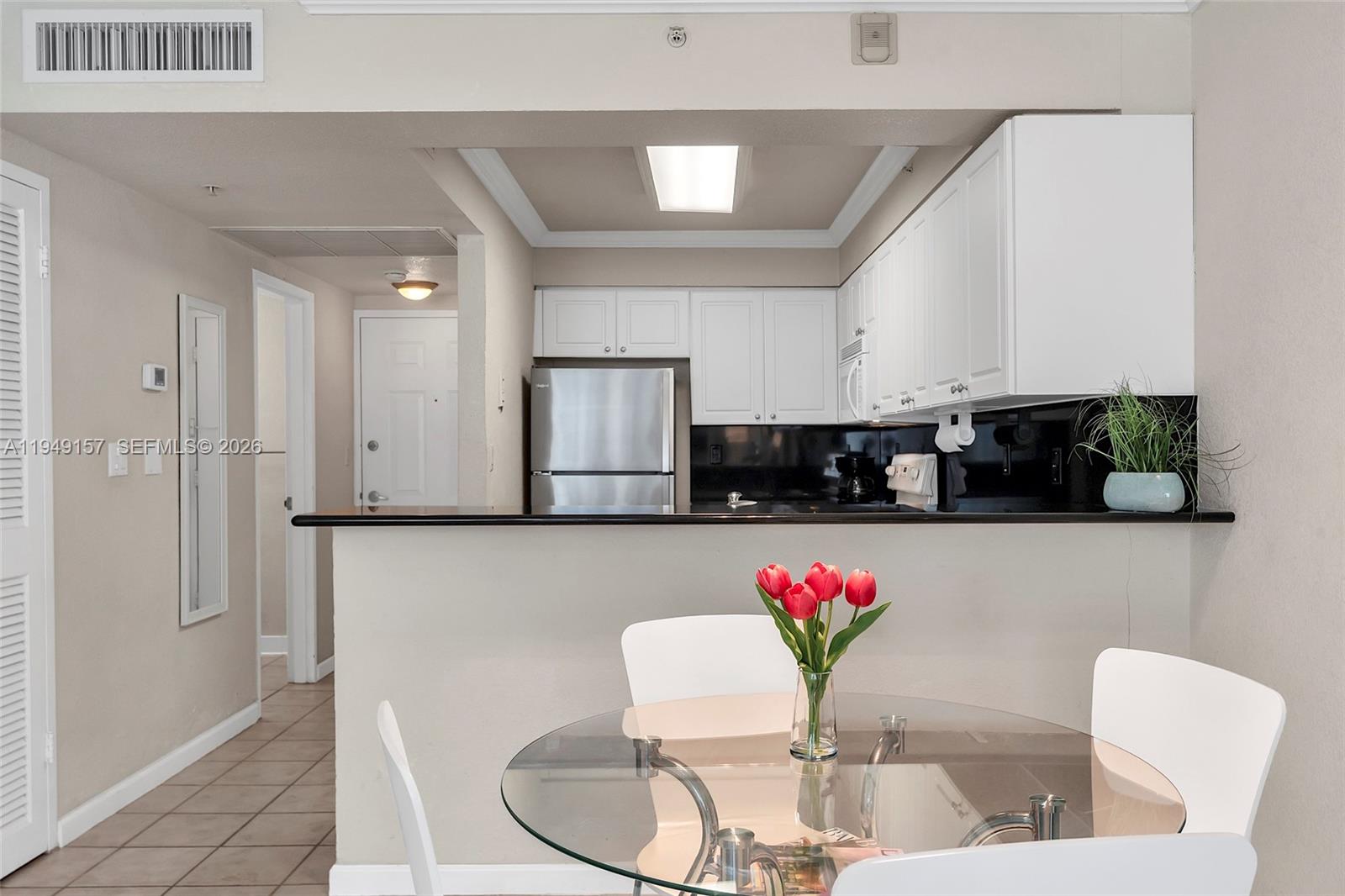 A kitchen with white cabinets and stainless steel appliances overlooks a dining area with a table — 2501 S Ocean Dr # 534, Hollywood FL 33019, HOLLYWOOD, FL