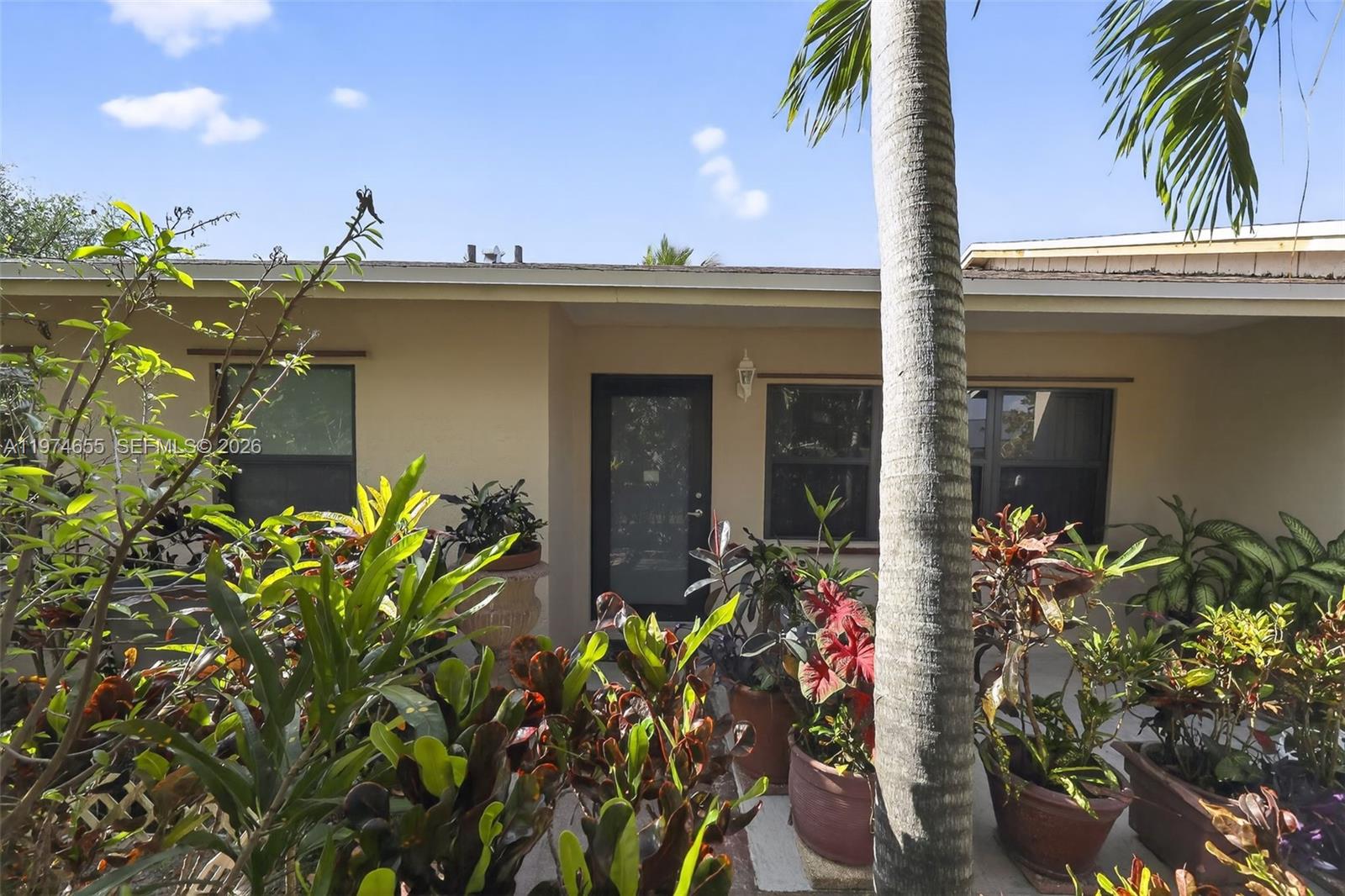 The exterior view shows a house entrance surrounded by numerous potted plants and a palm tree — 9522 Affirmed Ln, Boca Raton FL 33496, BOCA RATON, FL