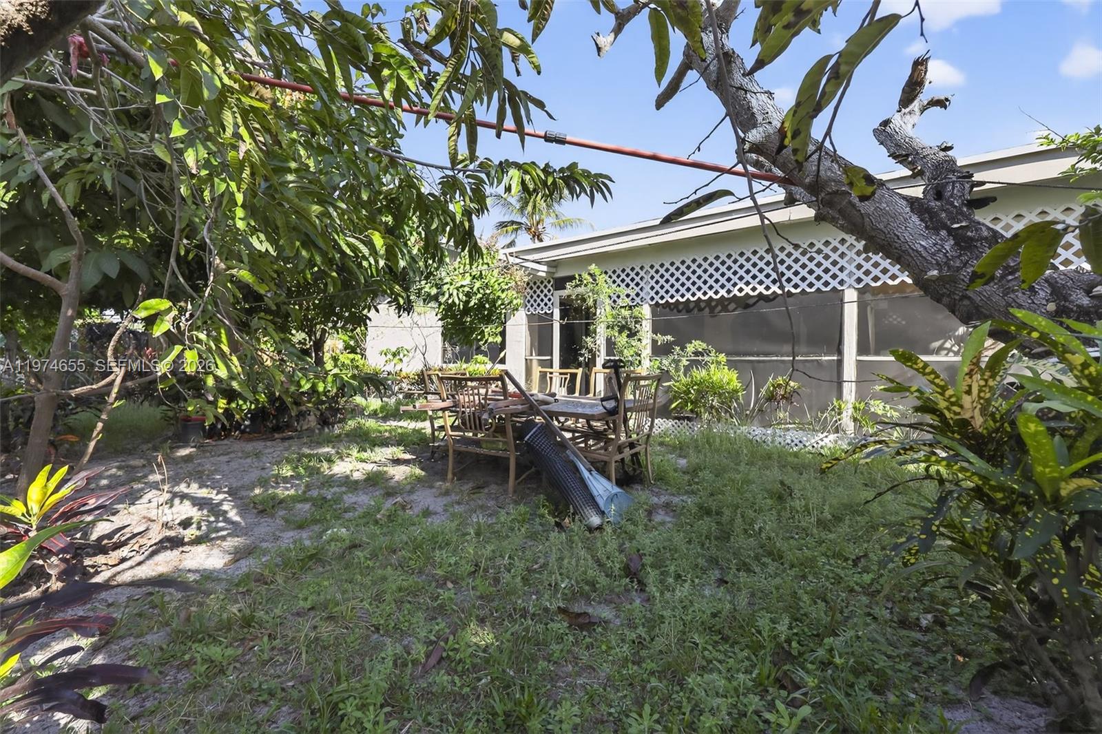 A backyard features a patio table and chairs set on a grassy, partially shaded lawn — 9522 Affirmed Ln, Boca Raton FL 33496, BOCA RATON, FL