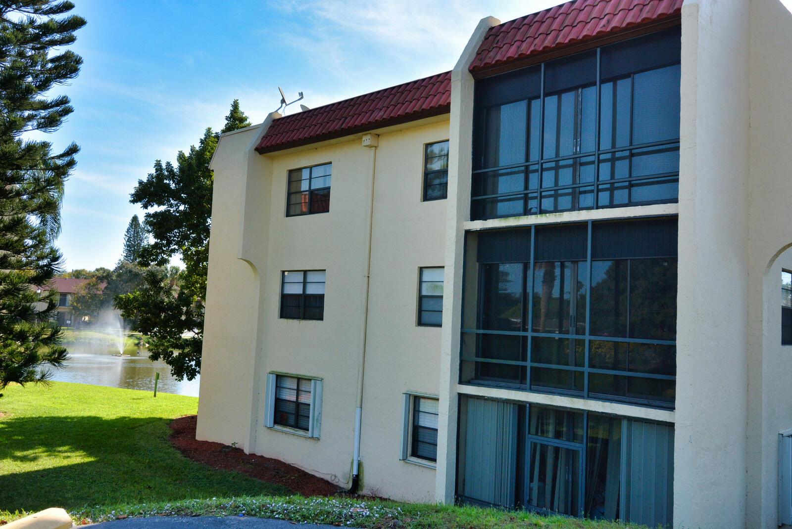 A three-story apartment building with a red tile roof, screened balconies, and a lake view — 2050 Oleander Boulevard # 306, Fort Pierce FL 34950, FORT PIERCE, FL