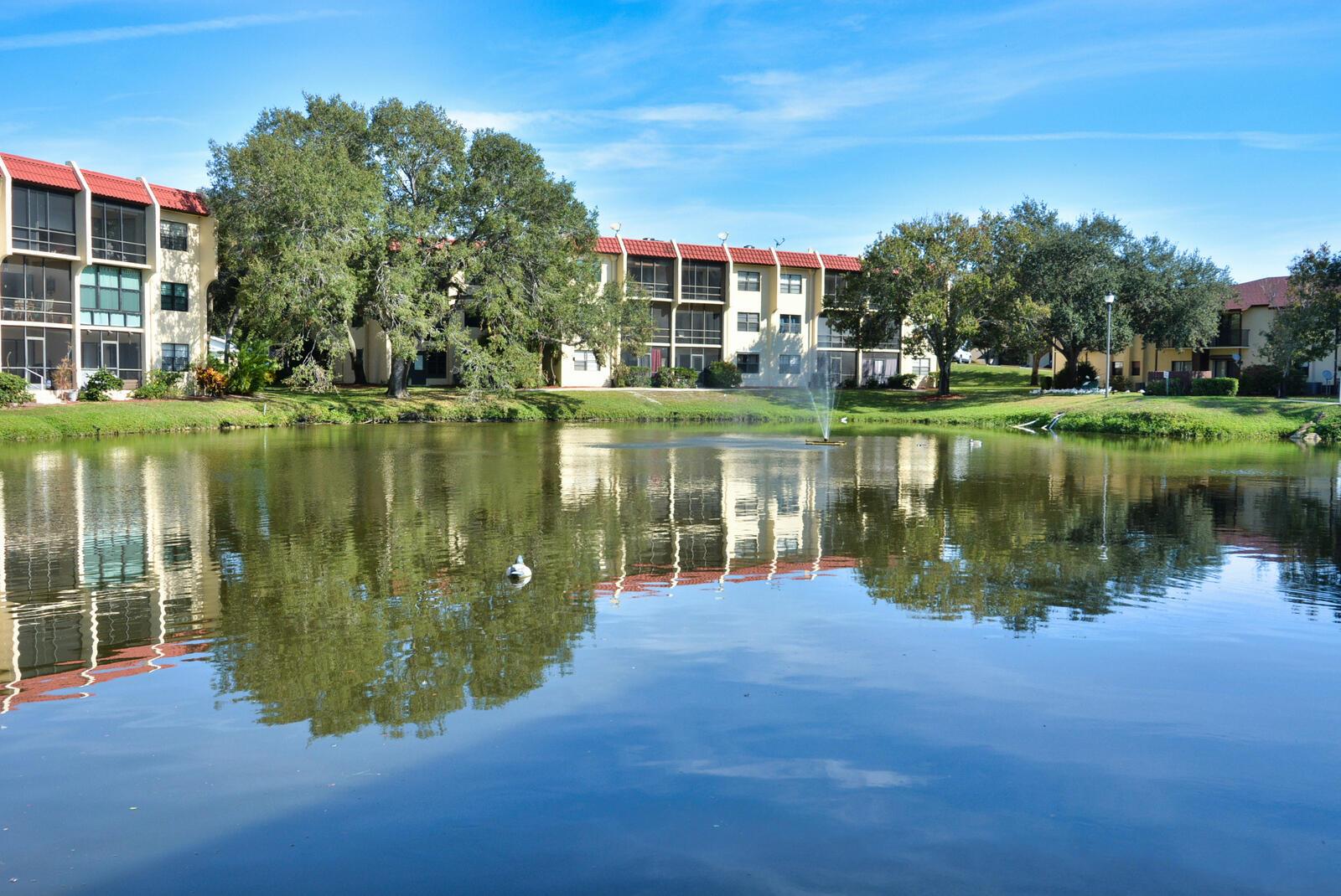 A pond reflects multi-story apartment buildings with red roofs and screened balconies — 2050 Oleander Boulevard # 306, Fort Pierce FL 34950, FORT PIERCE, FL