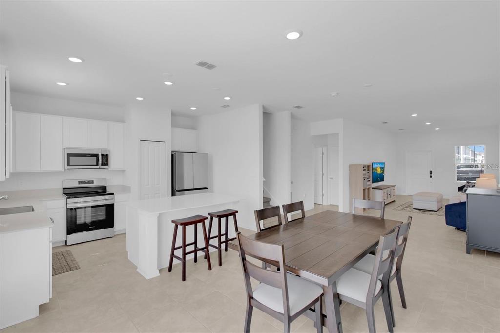 An open-concept kitchen and dining area with white cabinetry, stainless steel appliances, and tile flooring — 2845 PIERR STREET, DAVENPORT, FL