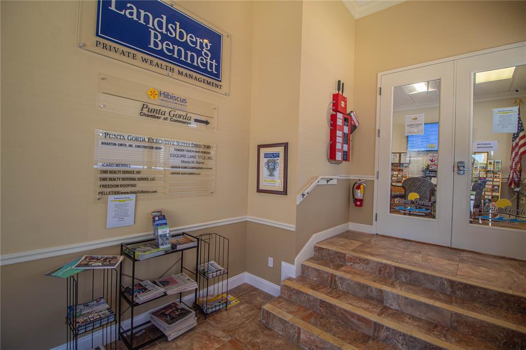 A small office lobby features a directory sign, a brochure rack, and tiled stairs — 252 W MARION AVENUE UNIT 113 & 115, PUNTA GORDA, FL