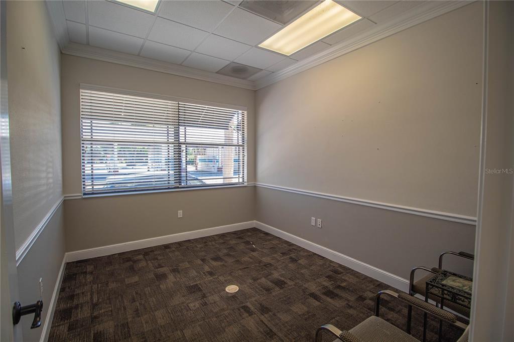 An empty office with gray walls, a patterned carpet, and large windows with closed blinds — 252 W MARION AVENUE UNIT 113 & 115, PUNTA GORDA, FL