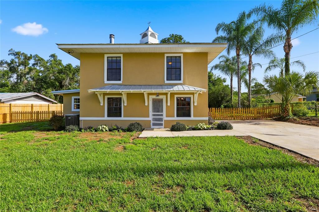 A two-story yellow house with a metal roof, cupola, and a front porch — 37715 DIXIE AVENUE, DADE CITY, FL