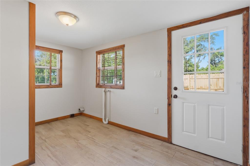 A room with light wood-look flooring, white walls, wood trim, two windows, and a door — 37715 DIXIE AVENUE, DADE CITY, FL