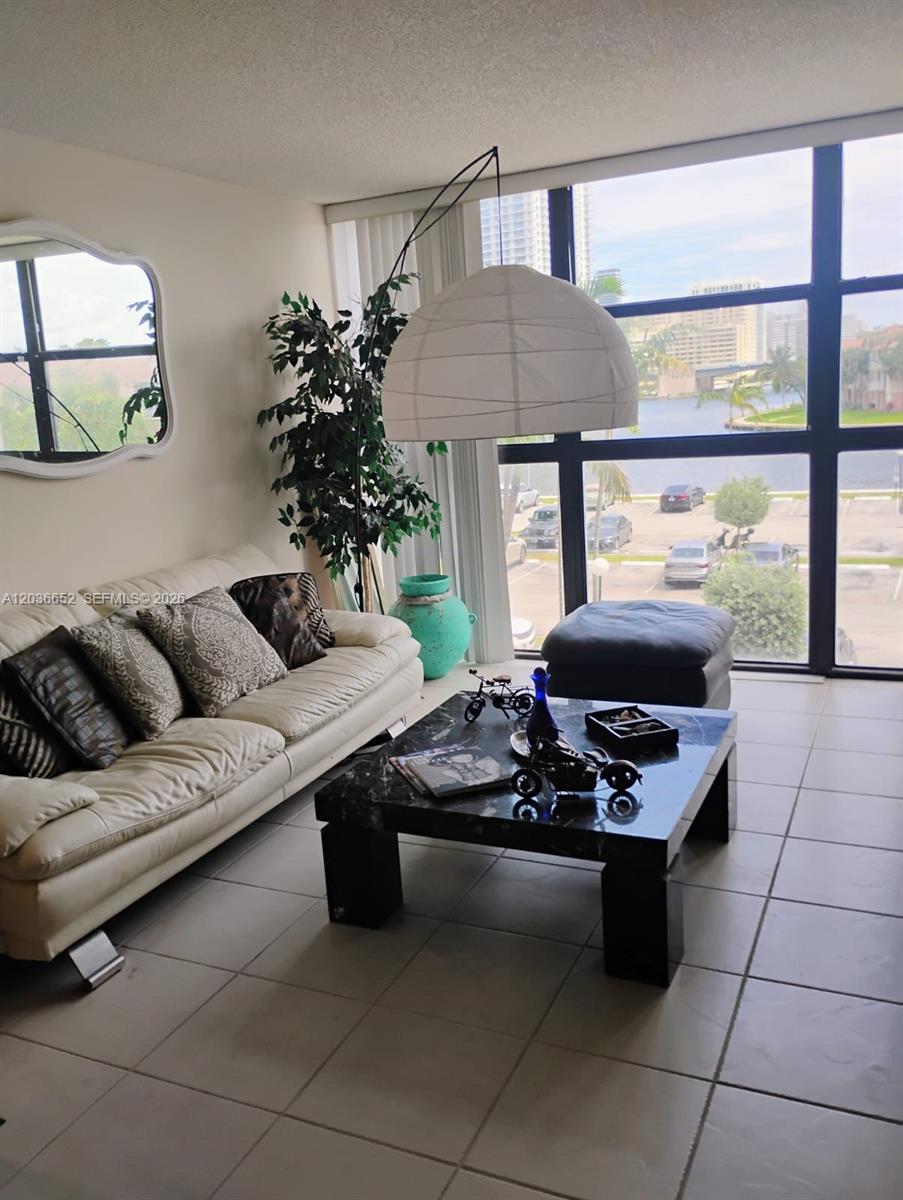 A living room features a white sofa, a black marble coffee table, and floor-to-ceiling windows — 200 Leslie Dr # 324, Hallandale Beach FL 33009, HALLANDALE BEACH, FL