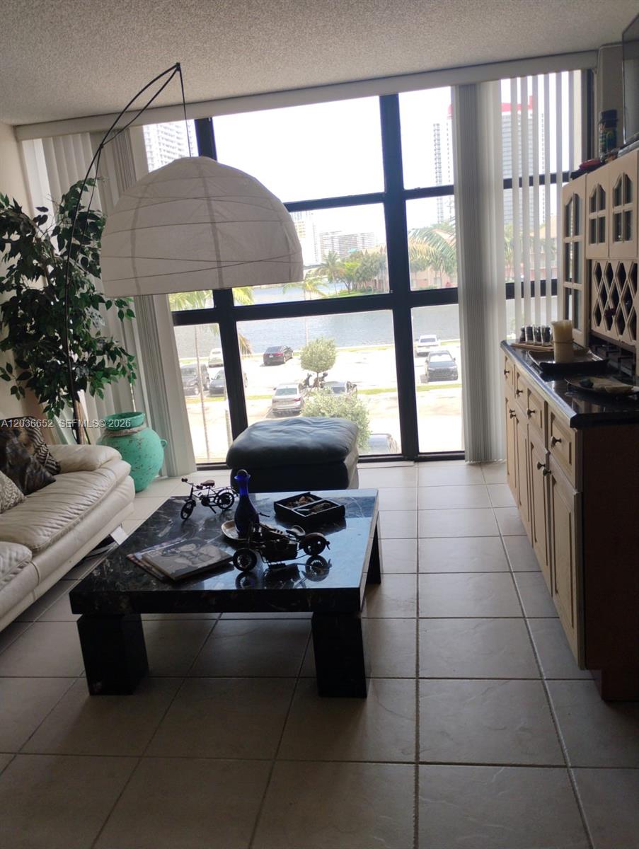A living room features a marble coffee table, a large pendant lamp, and floor-to-ceiling windows — 200 Leslie Dr # 324, Hallandale Beach FL 33009, HALLANDALE BEACH, FL