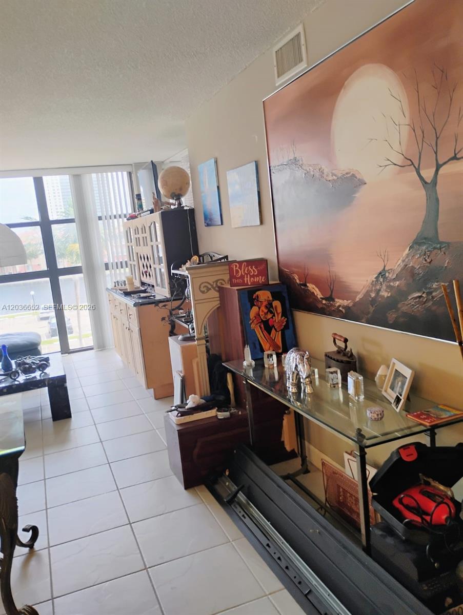 A living area features tiled floors, a large landscape painting, and a glass-topped console table — 200 Leslie Dr # 324, Hallandale Beach FL 33009, HALLANDALE BEACH, FL