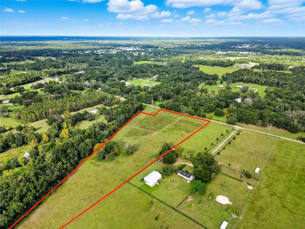 An aerial view shows a large, grassy rural lot outlined in red with a house — 0 POWERLINE ROAD, DADE CITY, FL