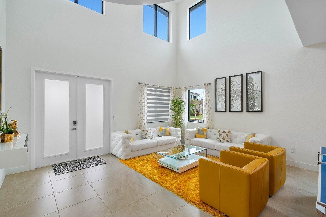A bright living room features white sofas, yellow armchairs, a shag rug, and high ceilings — 10780 Oceano Way, Parkland FL 33076, PARKLAND, FL