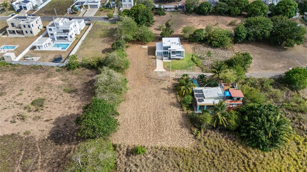 An aerial view shows a vacant lot situated between two modern houses and surrounding trees — PR 459 KM13.3 Bo. Bejucos INT CALLE LAS UVAS, ISABELA, PR